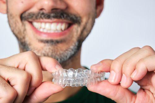 a man holding two clear aligners