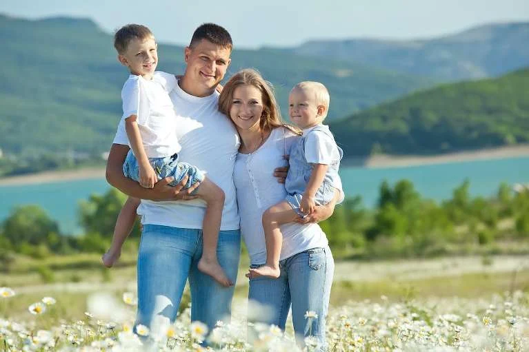 Family of four smiling outdoors by a lake