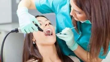 Dentist examining a young woman’s teeth in the dental chair